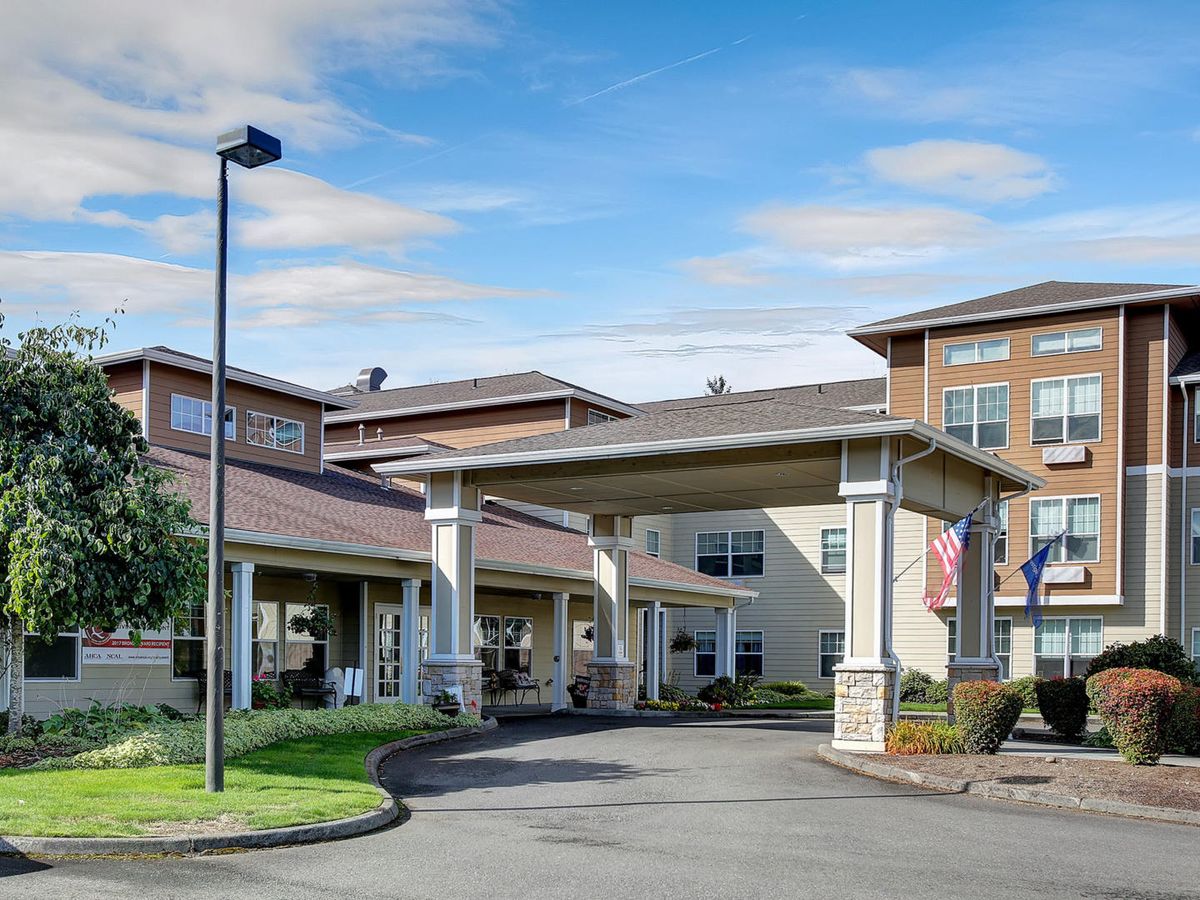 Entrance of a residential building with a driveway and landscaped surroundings.