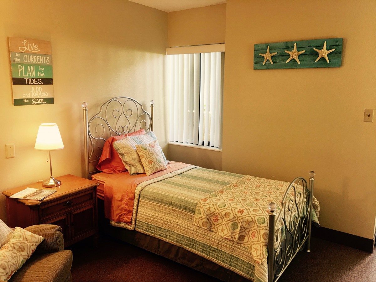 A cozy bedroom with a single bed, decorated with soft colors and starfish wall art.