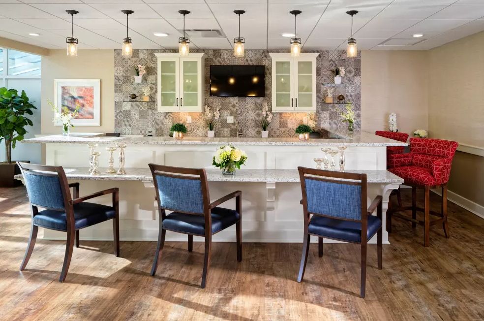 Modern kitchen interior with a large countertop, chairs, and pendant lighting.