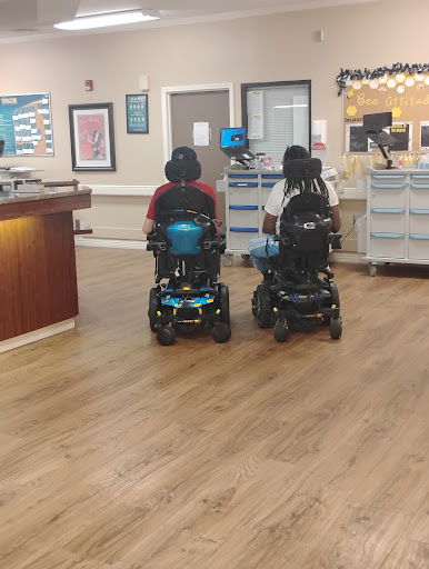 Two individuals in power wheelchairs navigating a healthcare facility.