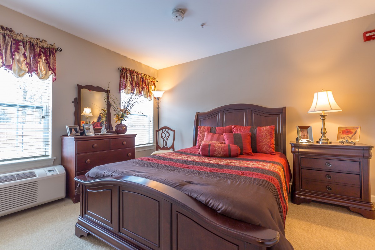 A cozy, traditional-style bedroom with wooden furniture and warm lighting.