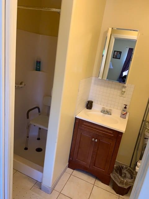 A small bathroom with a shower, sink, and mirror cabinet.