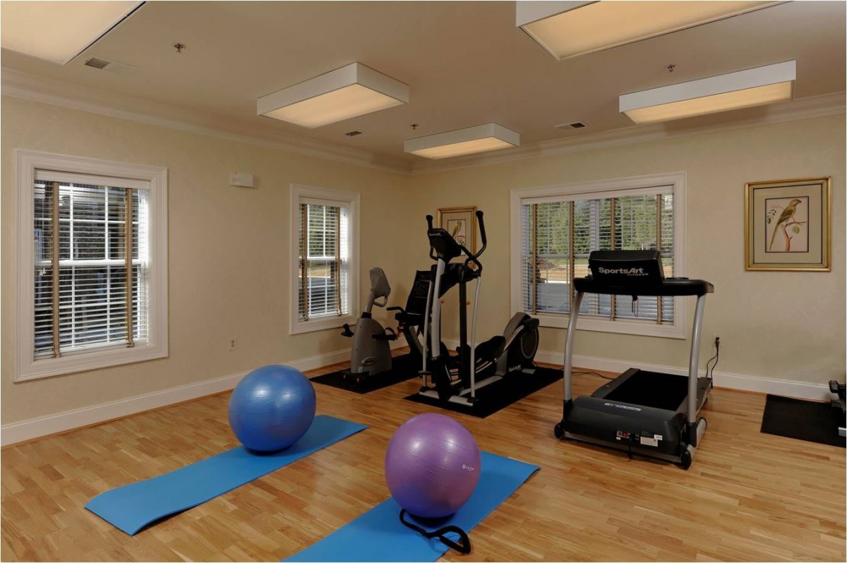 A compact home gym setup featuring various exercise equipment including yoga mats, exercise balls, a treadmill, and an elliptical machine.