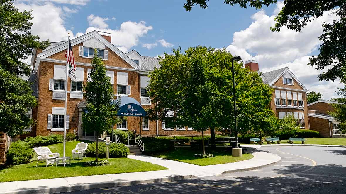 A hospital building with a lush green landscape on a sunny day.
