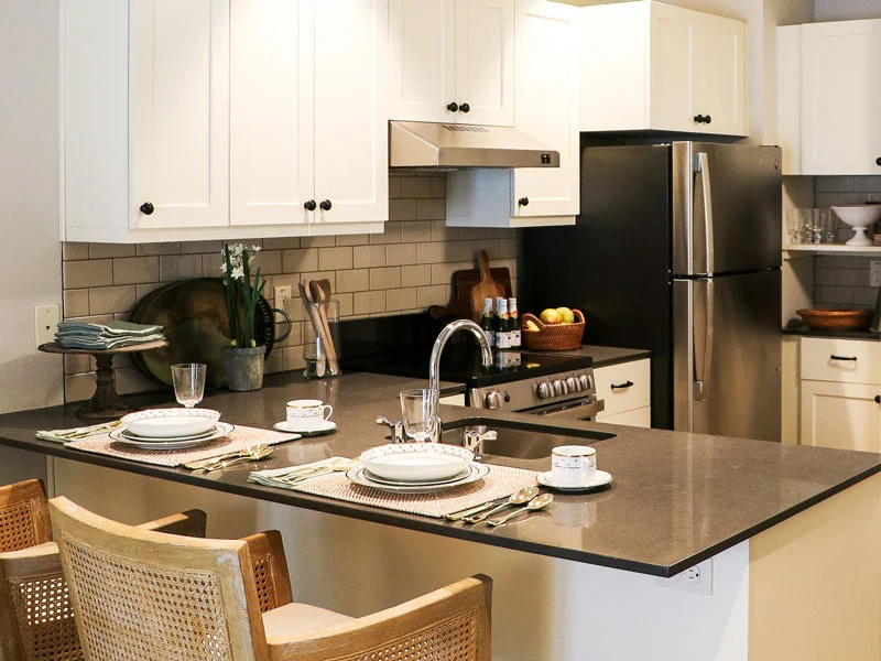 A modern kitchen featuring a stylish island with dining setup, complemented by white cabinets and stainless steel appliances.