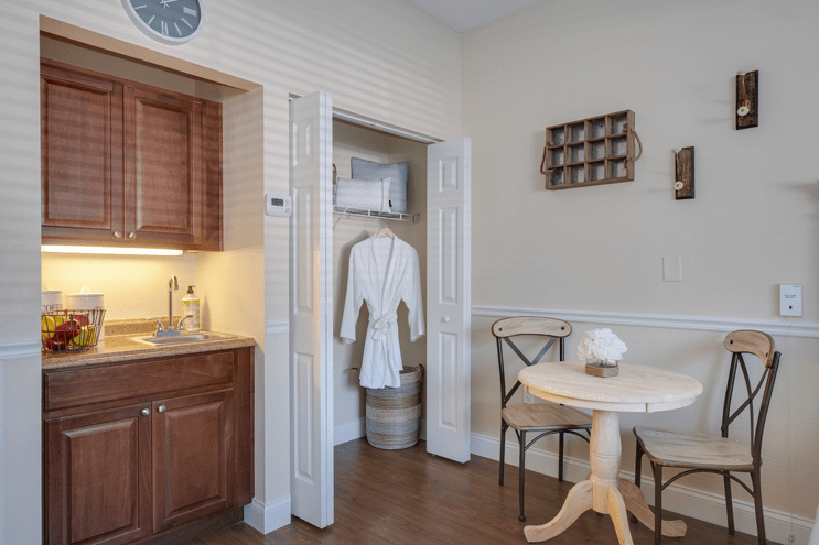 A cozy kitchenette area with a table, chairs, and a robe hanging in the closet.