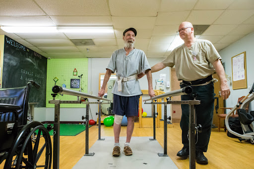 A patient receiving physical therapy assistance while practicing walking with the help of a therapist.