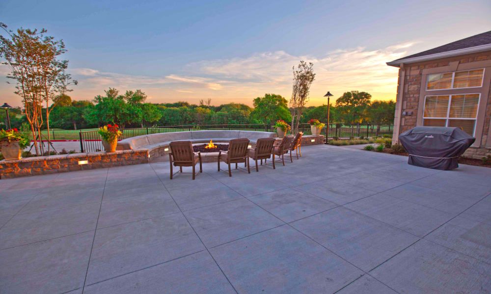 A spacious patio with chairs overlooking a picturesque sunset and lush landscape.