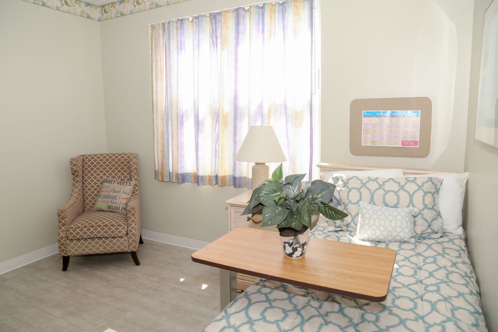 A hospital room with a bed, chair, and table.