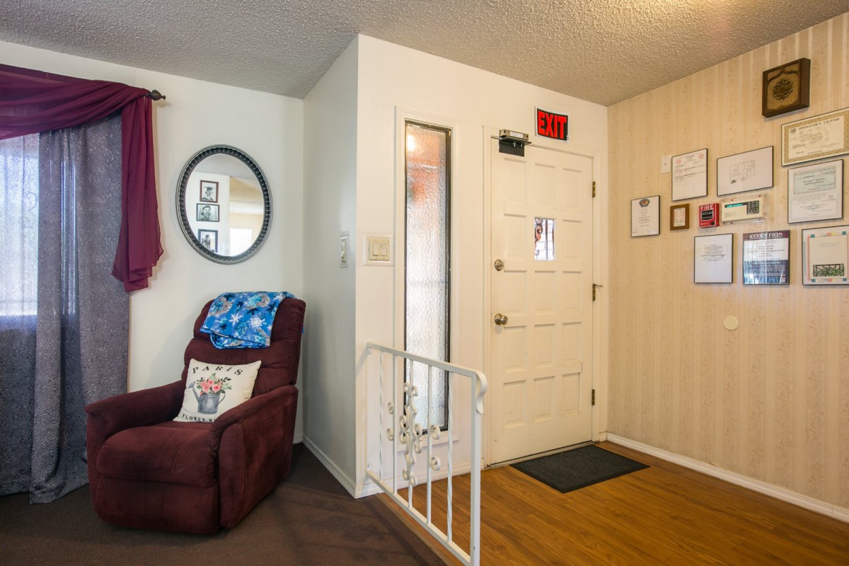 A cozy living room with a recliner chair, mirror on the wall, and a safety gate near the entryway.