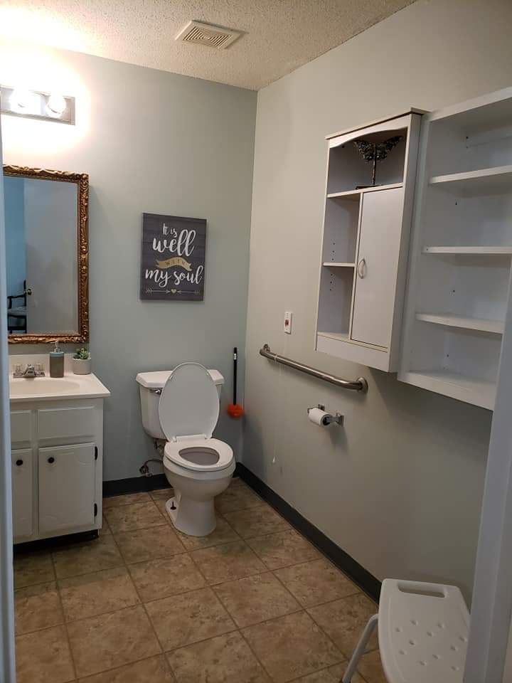 A well-organized bathroom with a toilet, sink, mirror, and storage cabinet.