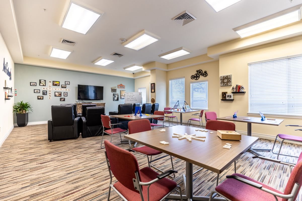 A well-lit meeting room equipped with tables, chairs, and a television.