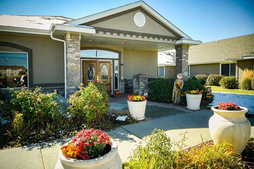 A beautifully landscaped building entrance featuring colorful flower arrangements.
