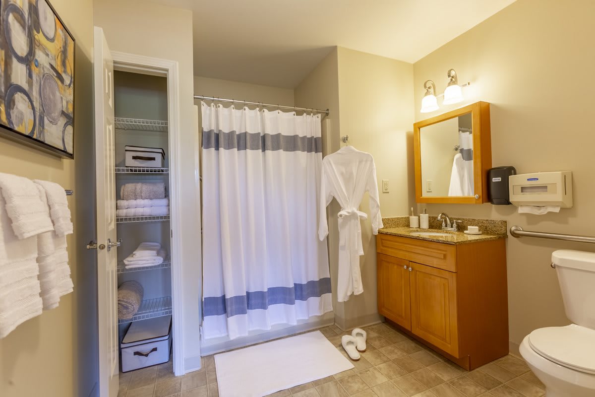 A well-organized bathroom with a shower, robe, and vanity area.