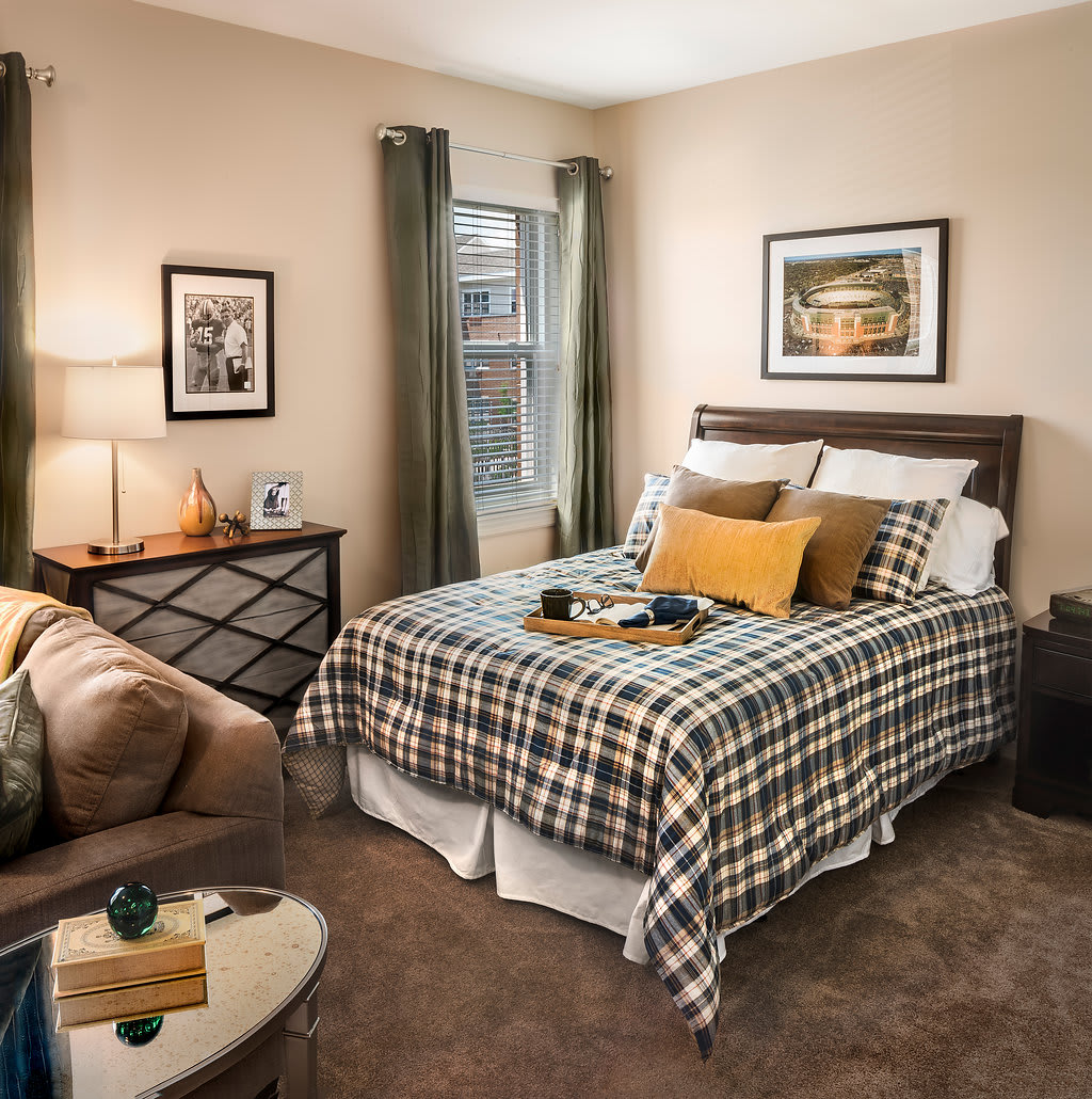 A cozy bedroom with plaid bedding, decorative pillows, and warm lighting.