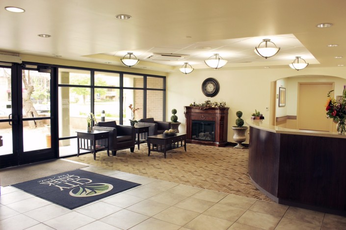 A spacious and well-lit lobby with a reception desk, seating area, and fireplace.