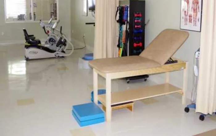 A physical therapy room with a treatment table and exercise equipment.