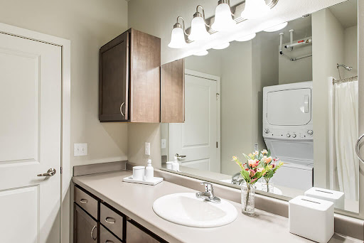 A well-lit modern bathroom featuring a sink, cabinets, and a laundry area.