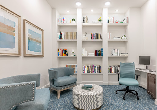 A cozy reading nook featuring modern furniture and a neatly arranged bookshelf.