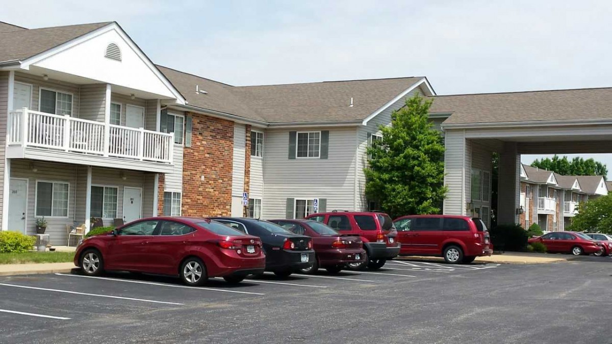 A residential apartment building with a parking lot full of cars.