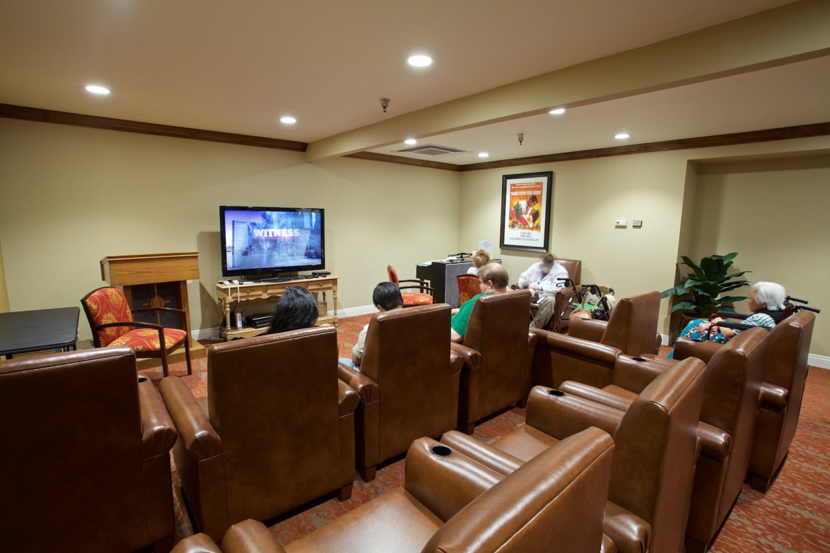 A cozy home theater with leather seating where people are watching television.