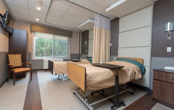 A modern hospital room with two patient beds and a curtain divider.