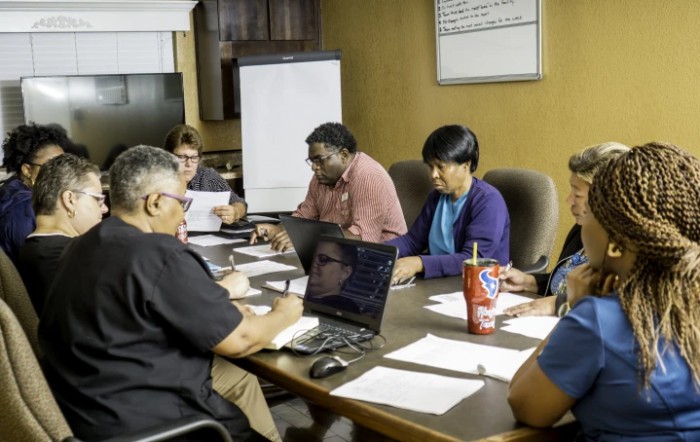 A group of people collaborating around a conference table in an office setting.