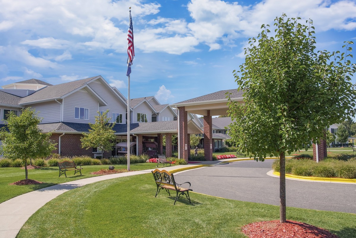 A view of a building with an American flag, surrounded by well-maintained landscaping and benches.