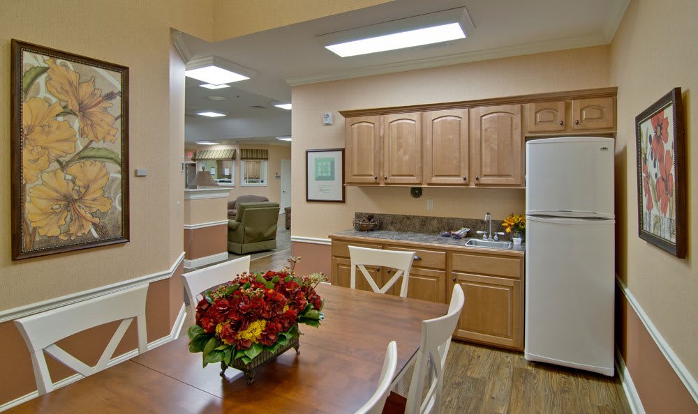 A modern kitchen and dining area with wooden cabinets, a table with chairs, and essential appliances.