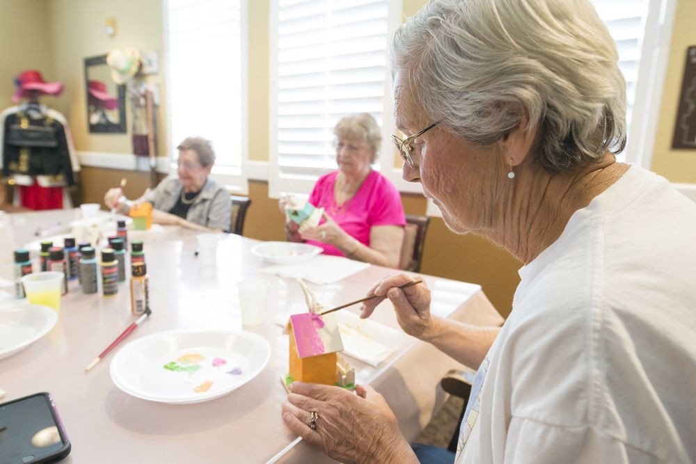 A group of seniors engaged in a painting activity, enjoying a creative indoor hobby together.