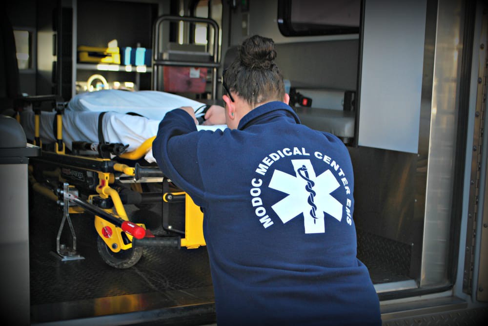 A medical worker is preparing a stretcher inside an ambulance.