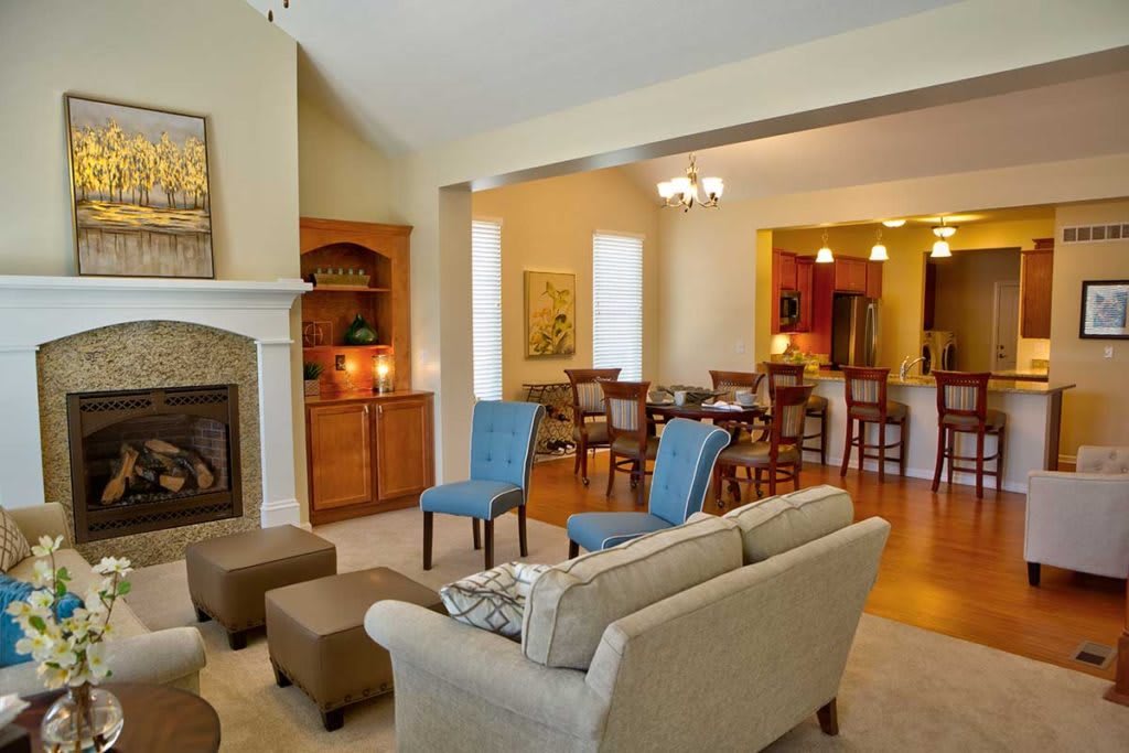 A cozy living room with an open dining area, featuring a fireplace and comfortable seating.