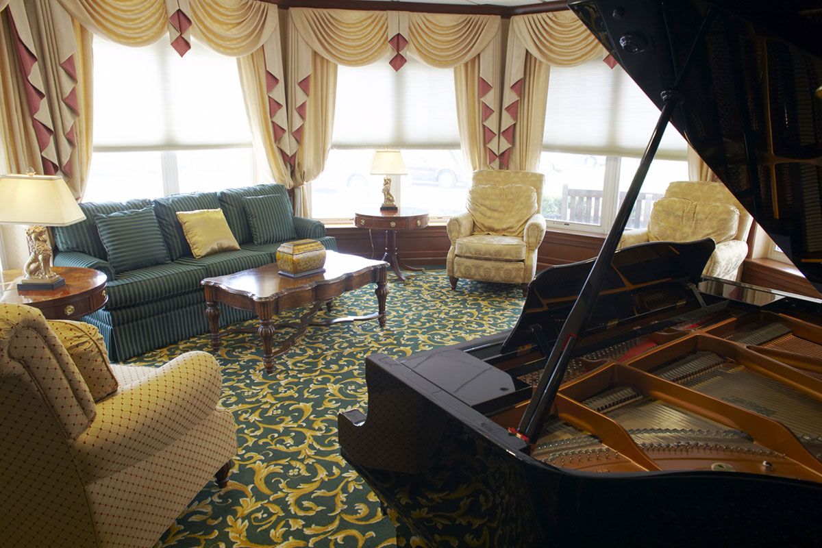 An elegant living room featuring a grand piano, plush seating, and luxurious decor.