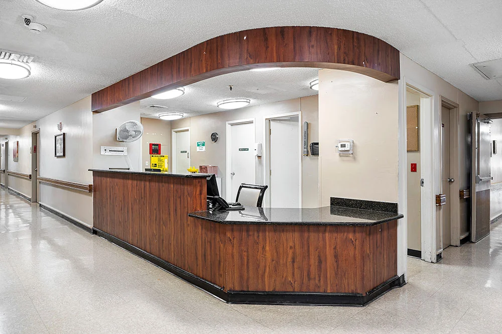 A hospital reception area with a wooden desk and computer equipment.