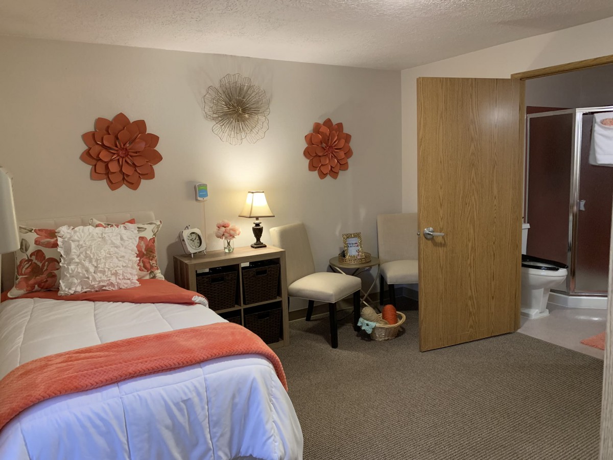 A cozy bedroom with wall decorations, a bed, and a small seating area.