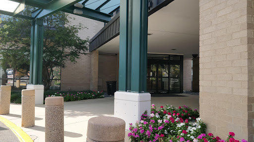 A welcoming entrance featuring a glass canopy and colorful flower beds.