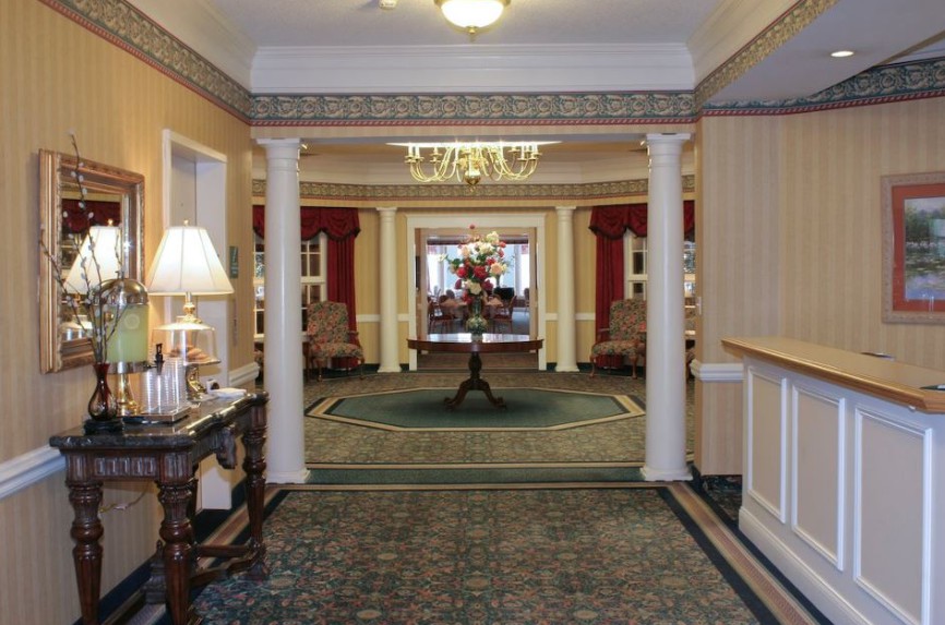 A hotel lobby featuring elegant columns, a chandelier, and decorative furniture.
