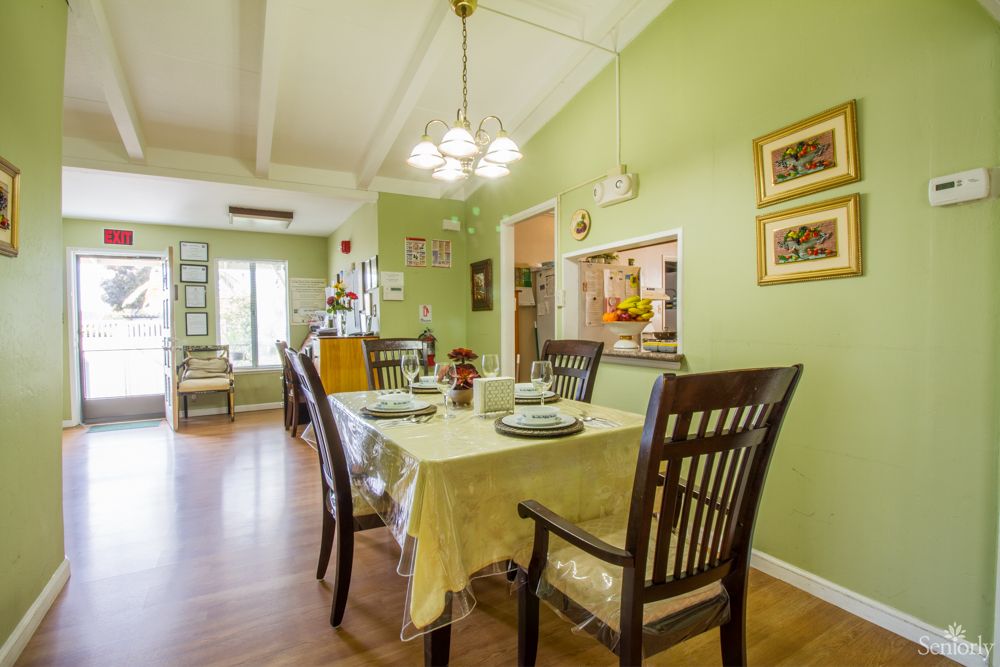 A cozy dining room with green walls, a chandelier, and a well-set table.