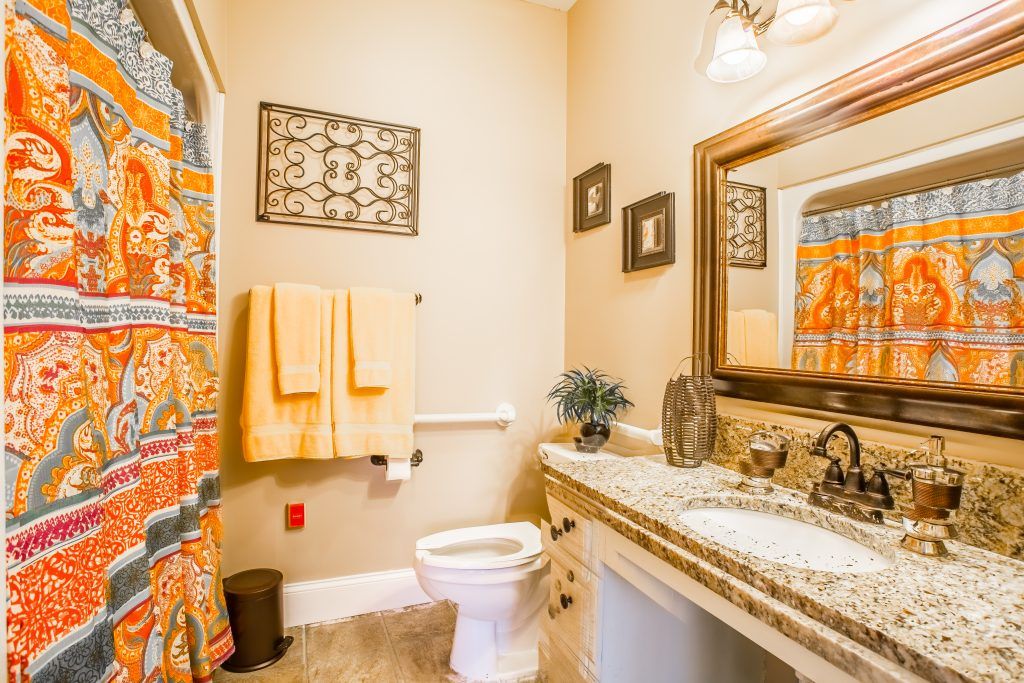 A well-decorated bathroom featuring a granite countertop, mirror, and colorful towels.