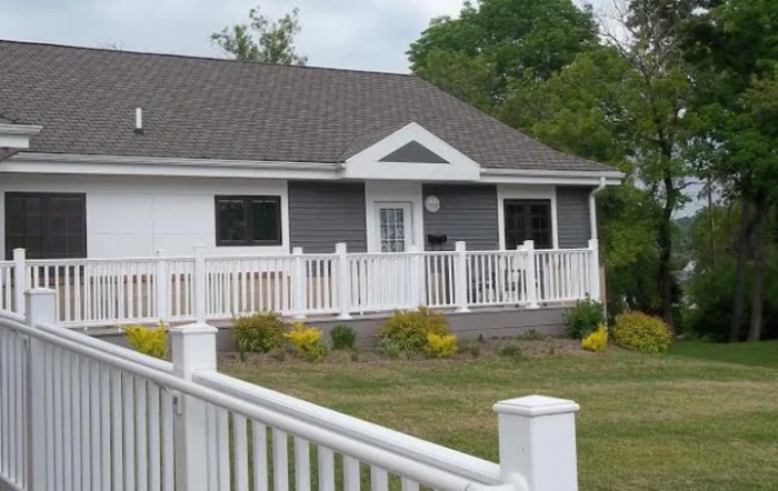 A suburban house with a white fence and landscaped front yard.