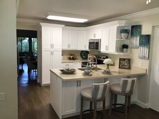 A modern kitchen with white cabinets and a central island featuring bar stools.