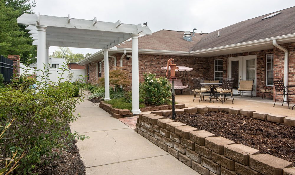 A cozy backyard patio with a pergola and garden, featuring outdoor seating and a walkway.