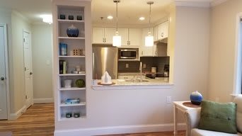 A modern open-concept kitchen with white cabinets and stainless steel appliances.
