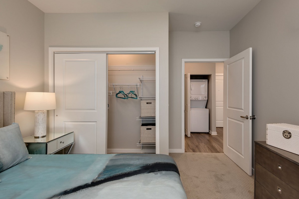 A cozy bedroom with an open closet and a view into the laundry area.