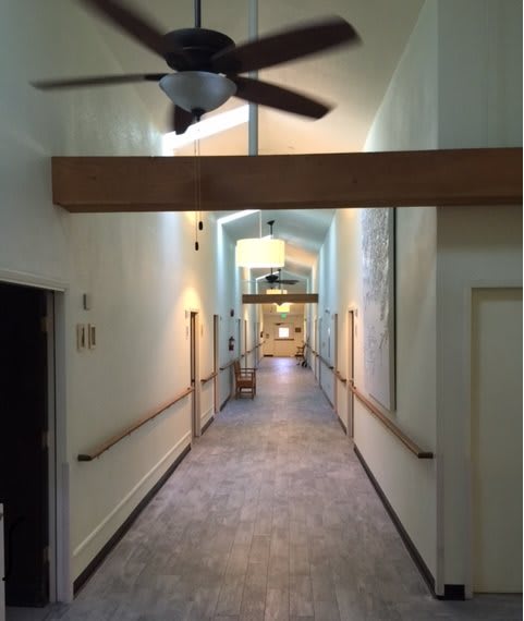 A well-lit corridor with wooden beams and ceiling fans.