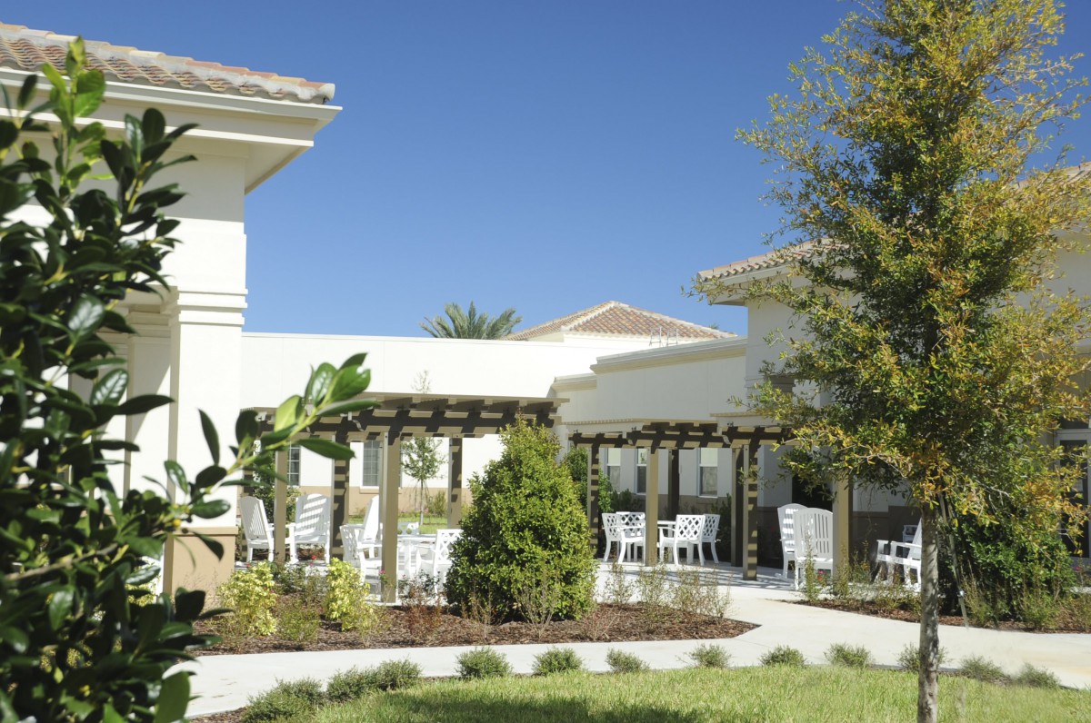 A beautifully landscaped outdoor area with a pergola and seating, adjacent to a building.
