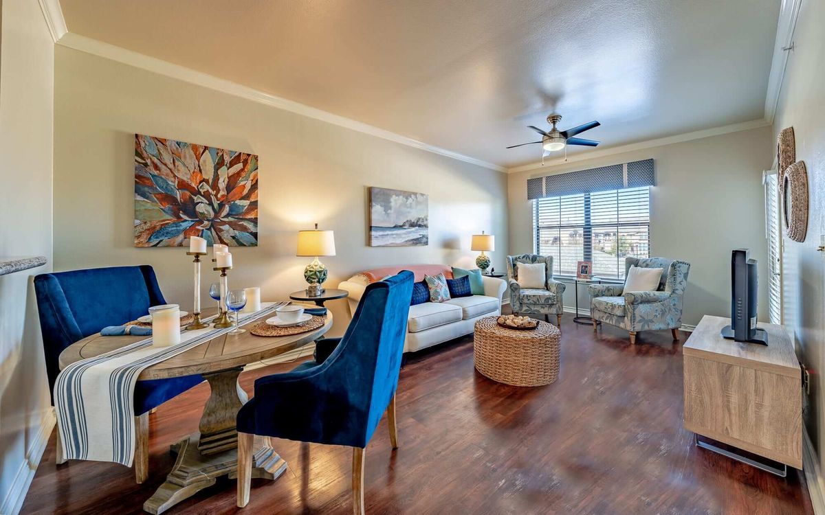 A modern living room with elegant furnishings and vibrant artwork, featuring a dining area and ample natural light.