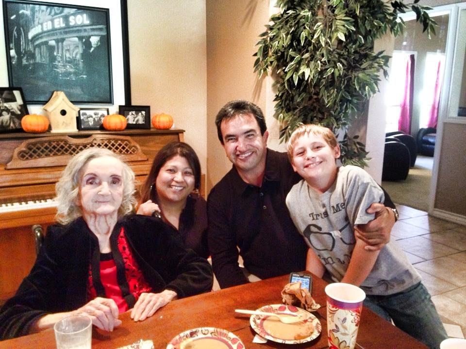 A family gathering around a table, smiling and enjoying each other's company.