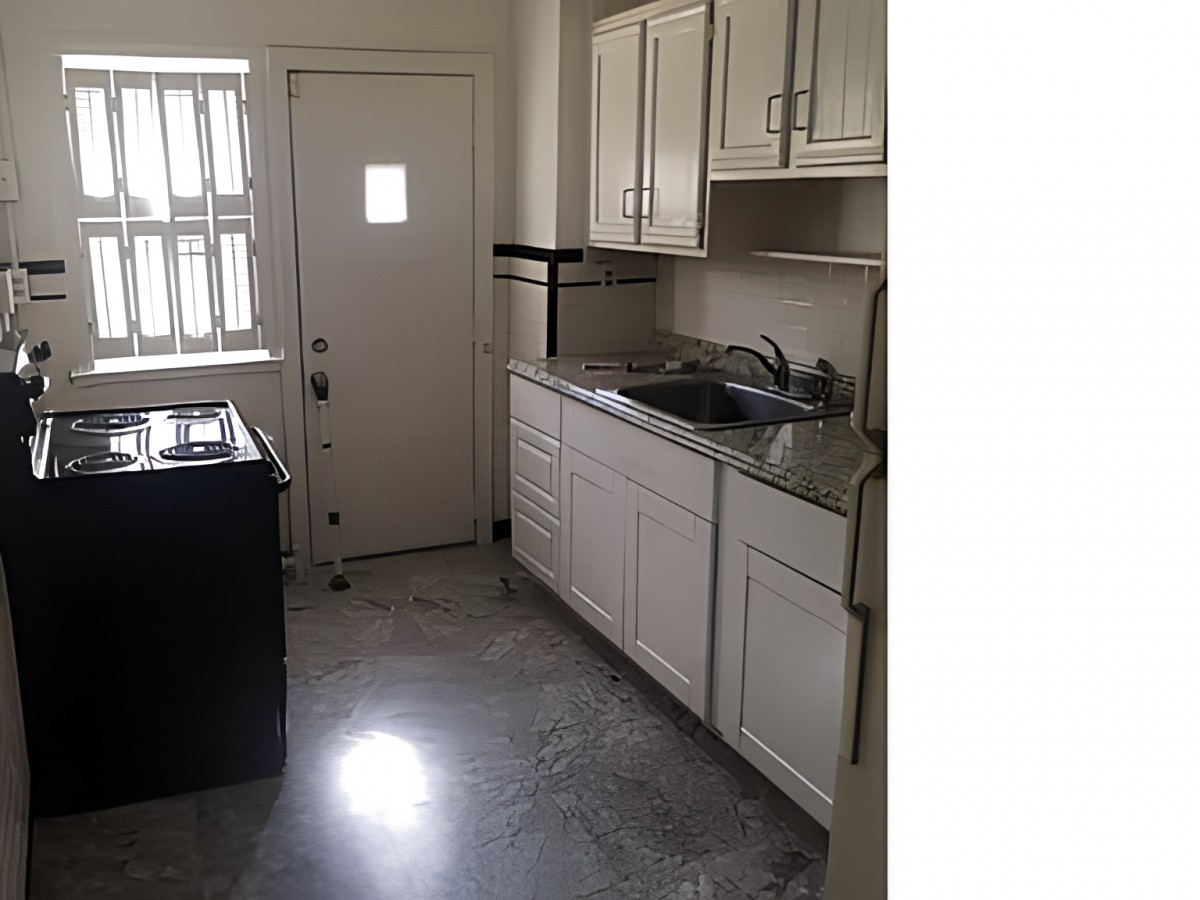 A compact apartment kitchen with white cabinets and a stainless steel sink.