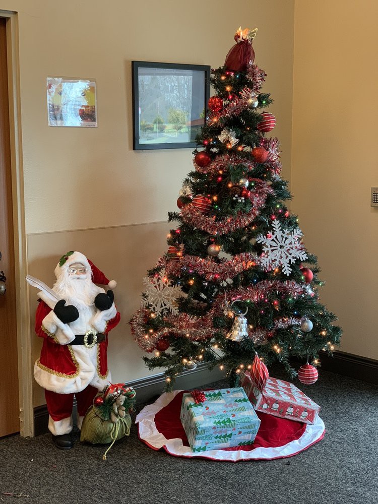 A festive indoor setup featuring a decorated Christmas tree, a Santa Claus figure, and wrapped gifts.